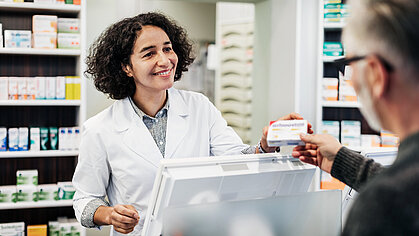 Apothekerin übergibt Kunden sein Medikament