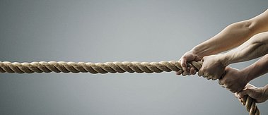 Hände ziehen gemeinsam an einem Seil