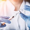Eine Spritze steckt in einer Imfpampulle und wird aufgezogen