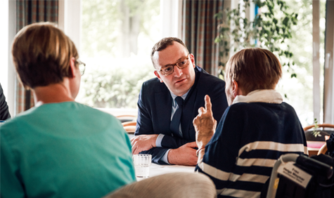 Jens Spahn im Gespräch mit einer Pflegekraft und einer Pflegebedürftigen