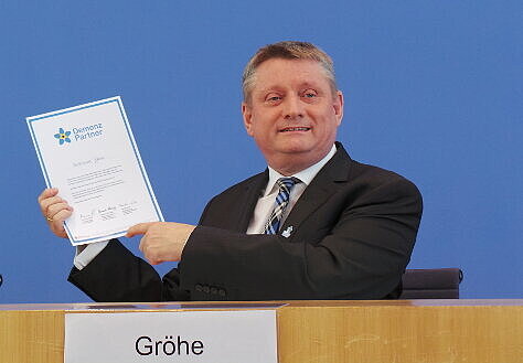 Bundesgesundheitsminister Hermann Gröhe hält seine Urkunde hoch, die er bei seiner Schulung zum Demenz Partner erhalten hat.