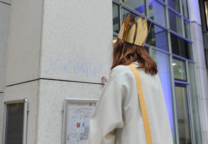 Ein Sternsinger schreibt den jährlichen Segen "C+M+B" an eine der Eingangssäulen des Ministeriums.